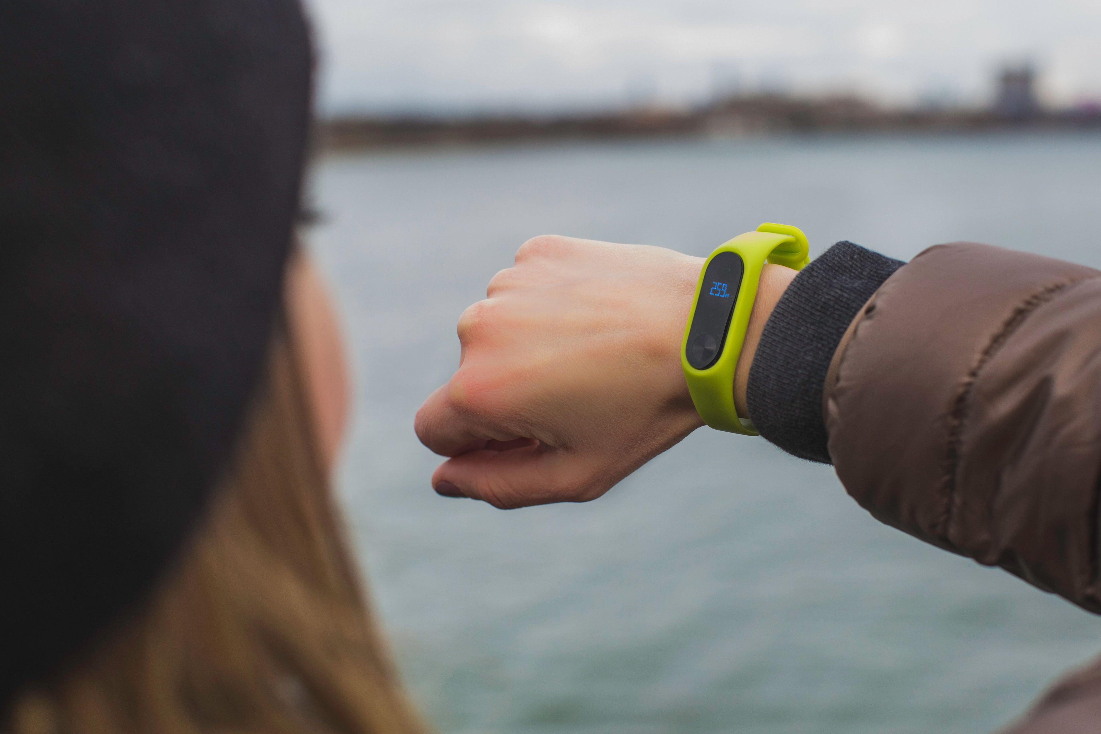 Woman outdoors checking the time on her smartwatch by a lake — editorial lifestyle photography, licensed CC0 via Pexels